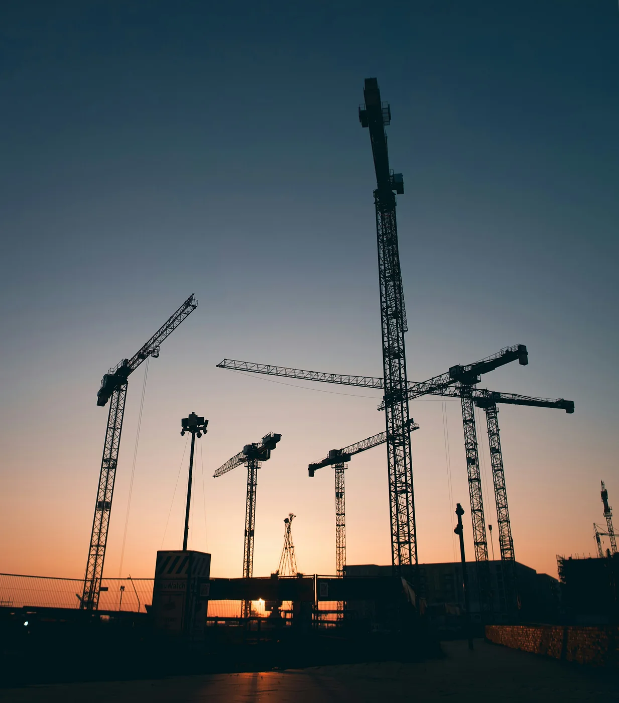 Grúas de construcción en un proyecto inmobiliario al atardecer