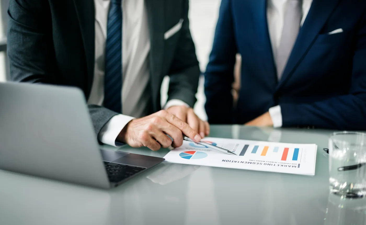 Profesionales revisando reportes financieros junto a una laptop