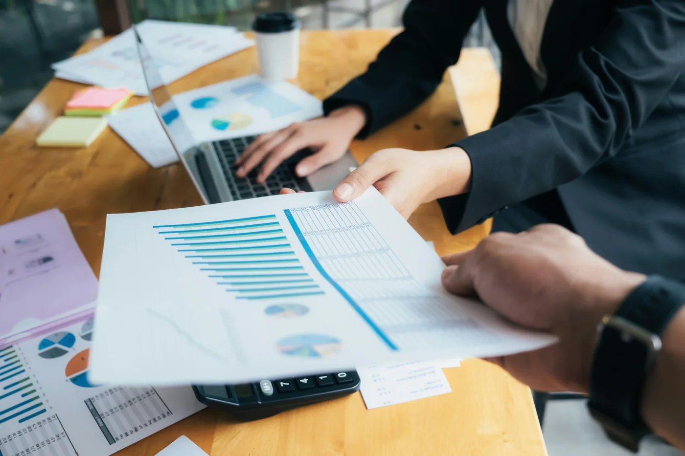 Equipo comparando reportes y gráficas financieras sobre una mesa