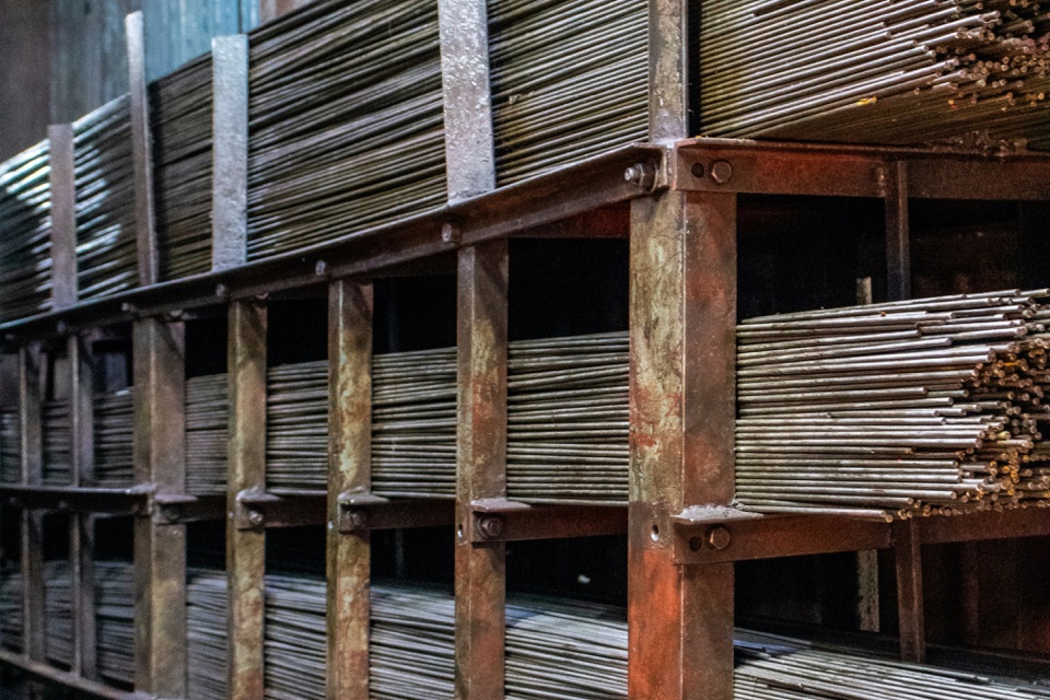 Barras de acero apiladas en estanterías industriales; fotografía ilustrativa