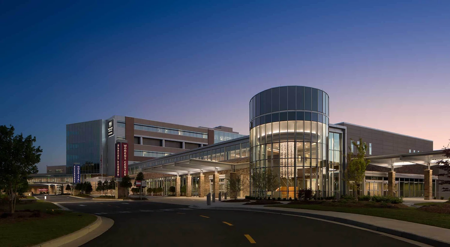 Exterior de un hospital con acceso acristalado al atardecer