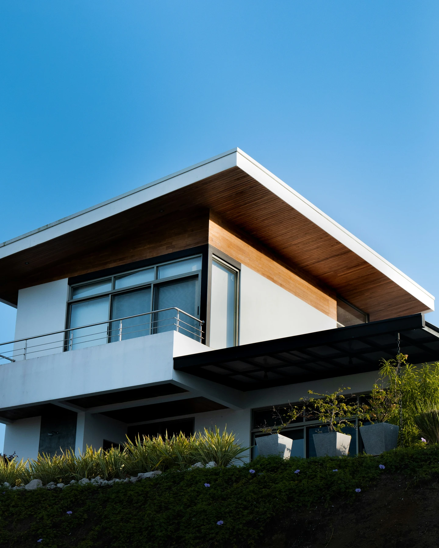 Casa contemporánea con fachada de madera, balcones y jardín